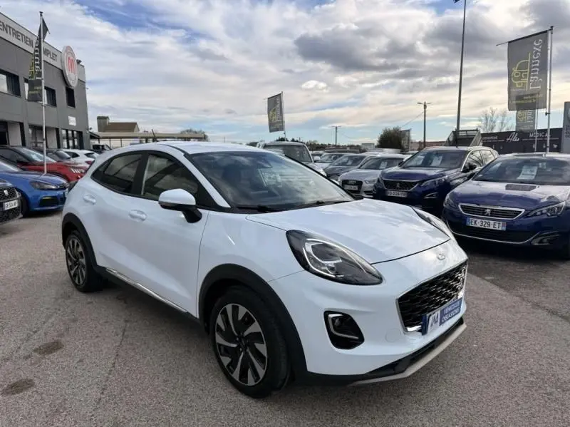 Ford Puma blanc en 3/4 avant droit, avec calandre noire et jantes alliage distinctives, sur parking extérieur.