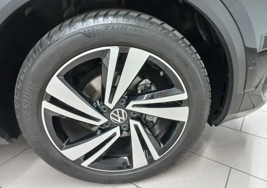 Gros plan sur la roue avant droite du Volkswagen T-Roc noir intense, avec jante alliage bicolore et pneu Bridgestone.