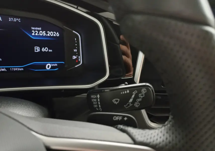 Vue rapprochée du tableau de bord numérique et du commodo d’essuie-glace du Volkswagen T-Roc noir intense 2025.