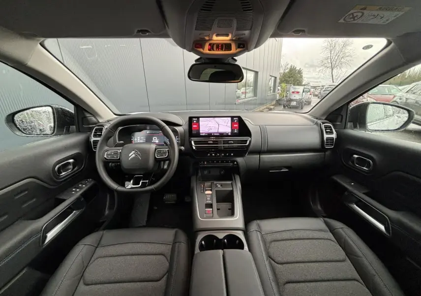 Vue intérieure avant du Citroën C5 Aircross 2025, tableau de bord noir avec écran tactile central et volant multifonction.