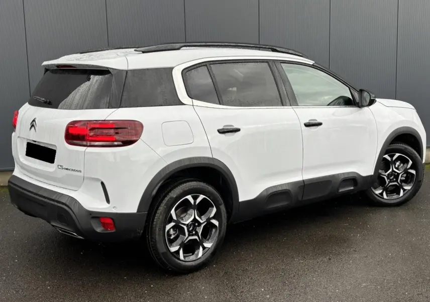 Vue 3/4 arrière droite du Citroën C5 Aircross blanc Okénite avec jantes alliage bi-ton et barres de toit noires.
