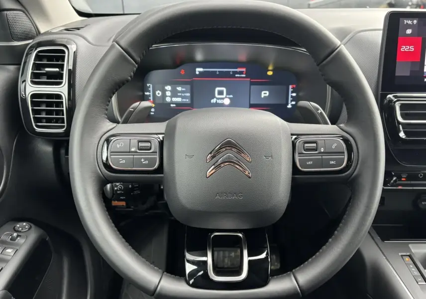Vue centrée sur le volant cuir noir du Citroën C5 Aircross 2025 avec tableau de bord numérique et écran tactile latéral.