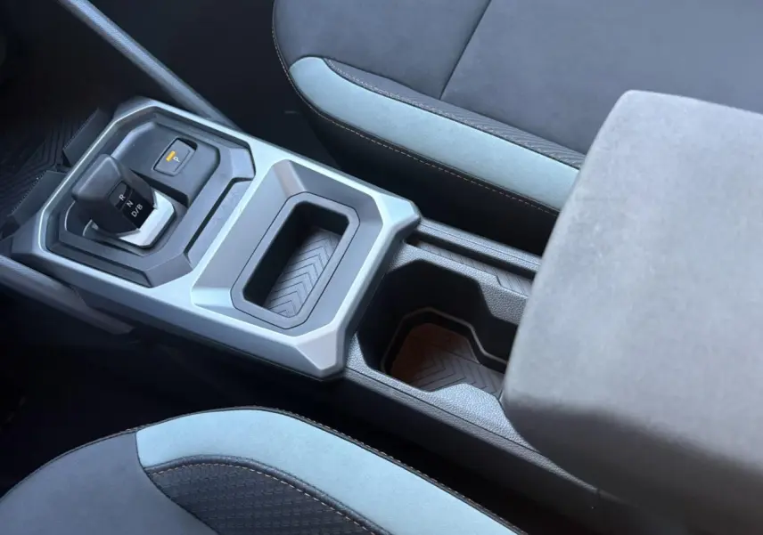 Vue plongeante sur la console centrale grise et les sièges TEP MicroCloud noirs avec surpiqûres marron du Dacia Duster 2026.