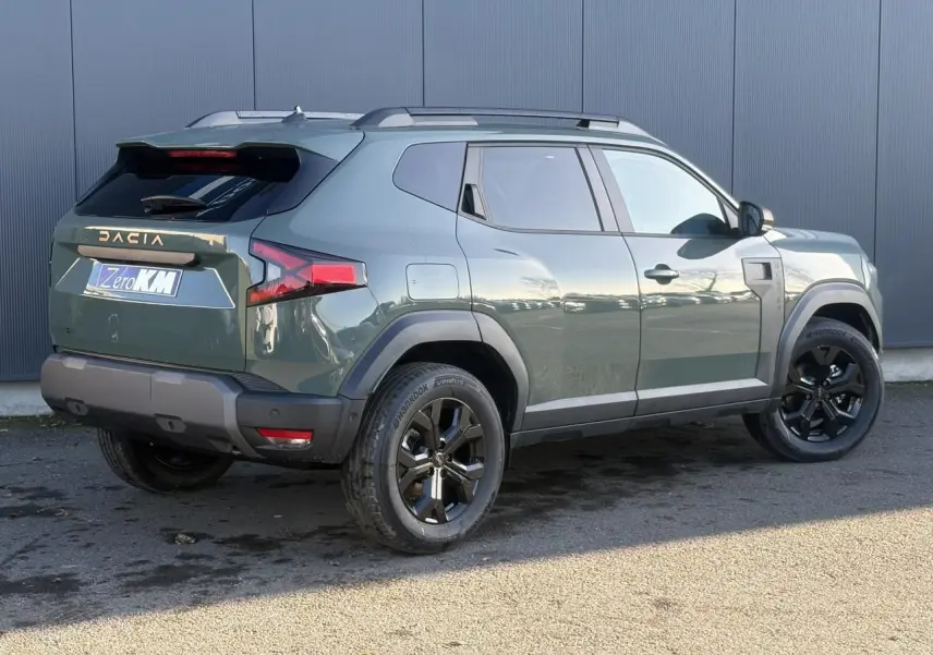 Vue 3/4 arrière droite du Dacia Duster 2026 kaki lichen avec jantes alliage noires et barres de toit longitudinales.