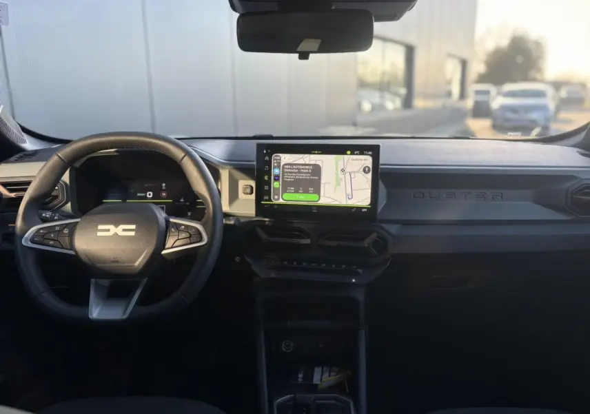 Vue frontale de l'habitacle du Dacia Duster 2026, tableau de bord digital et écran tactile central allumé.
