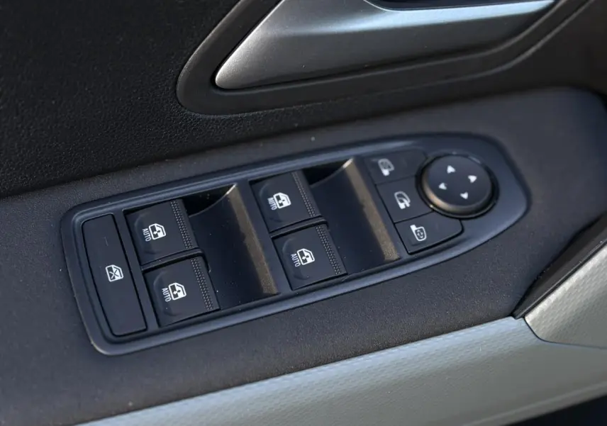 Gros plan sur les commandes des vitres électriques et rétroviseurs sur la porte côté conducteur du Dacia Duster 2026.