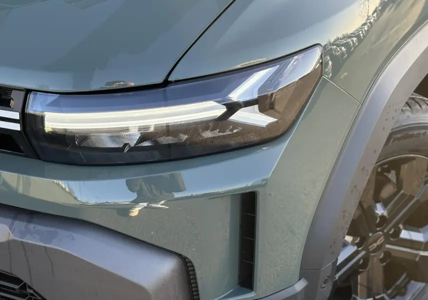 Gros plan sur le phare avant droit du Dacia Duster 2026 kaki lichen avec jante alliage noire et détails du pare-chocs.