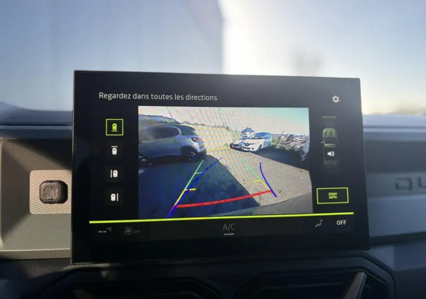 Écran tactile intérieur montrant la caméra multivues du Dacia Duster kaki en vue arrière avec guidage de stationnement.