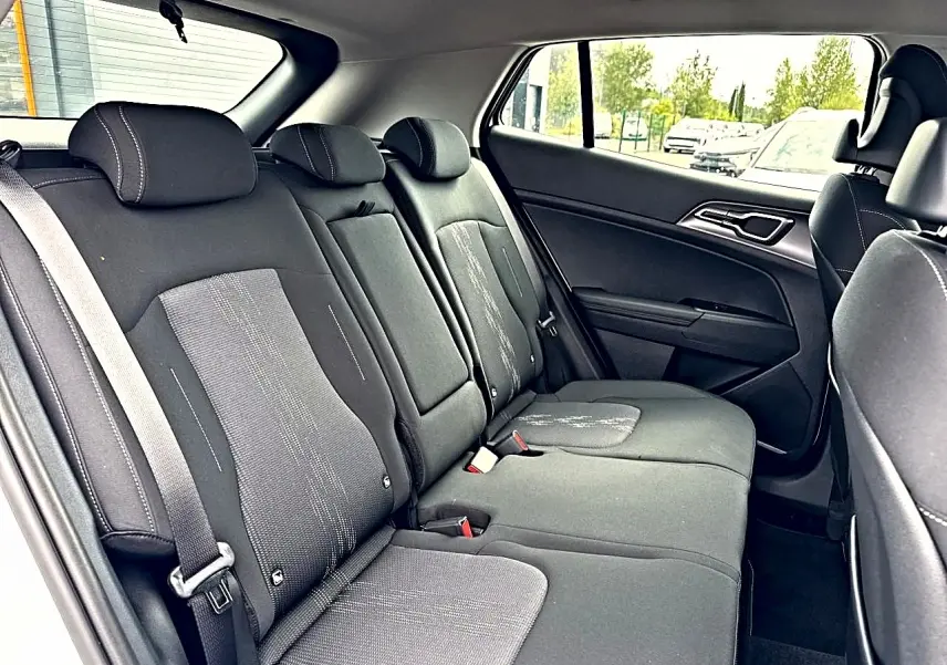 Vue latérale droite de la banquette arrière noire du Kia Sportage 1.6 hybride 239 active avec appuie-têtes et ceintures visibles.