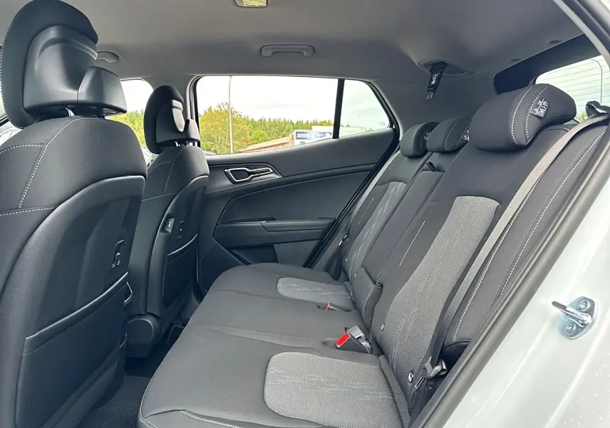 Vue intérieure côté droit sur la banquette arrière noire et grise du Kia Sportage blanc 2026, avec appuie-têtes réglables.
