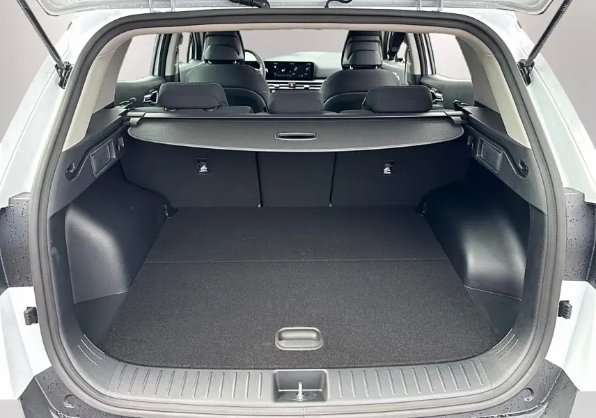 Coffre ouvert vu de l'arrière d'un KIA Sportage blanc 2026 avec banquette arrière et tablette cache-bagages.