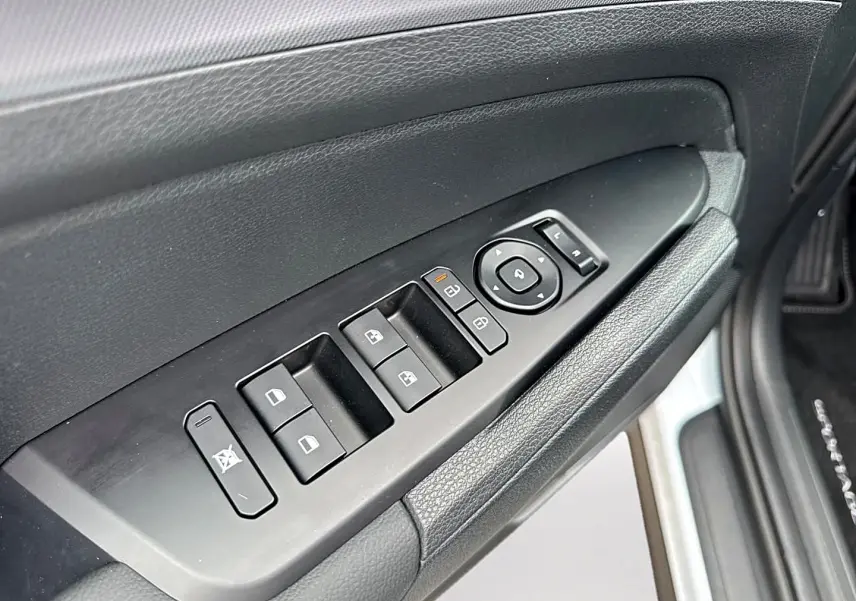 Vue rapprochée de la porte avant gauche du Kia Sportage blanc, avec commandes électriques des vitres et rétroviseurs.