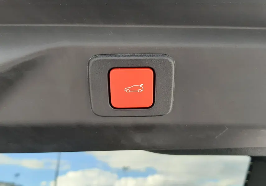 Bouton rouge de fermeture électrique du hayon visible à l'intérieur du coffre du Peugeot 3008 gris titane.