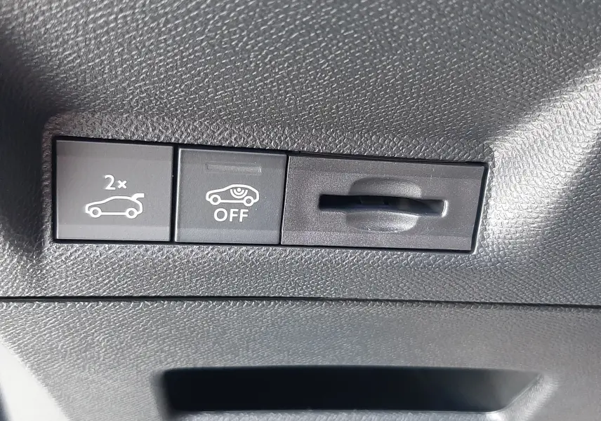 Détail intérieur du tableau de bord du Peugeot 3008 1.2 Hybrid, montrant les boutons de commande du hayon et de l'alerte de sécurité.