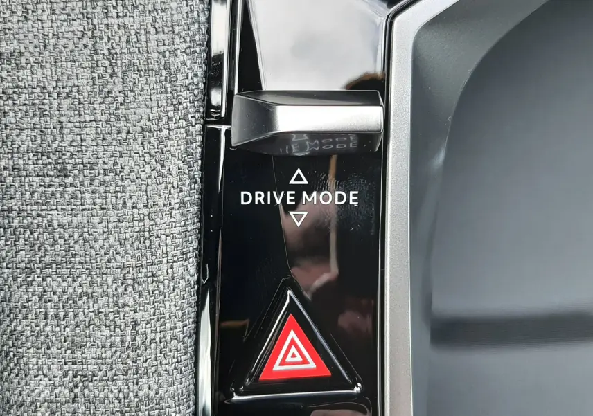 Détail du bouton Drive Mode et du signal de détresse sur la console noire brillante d’un Peugeot 3008 hybride.