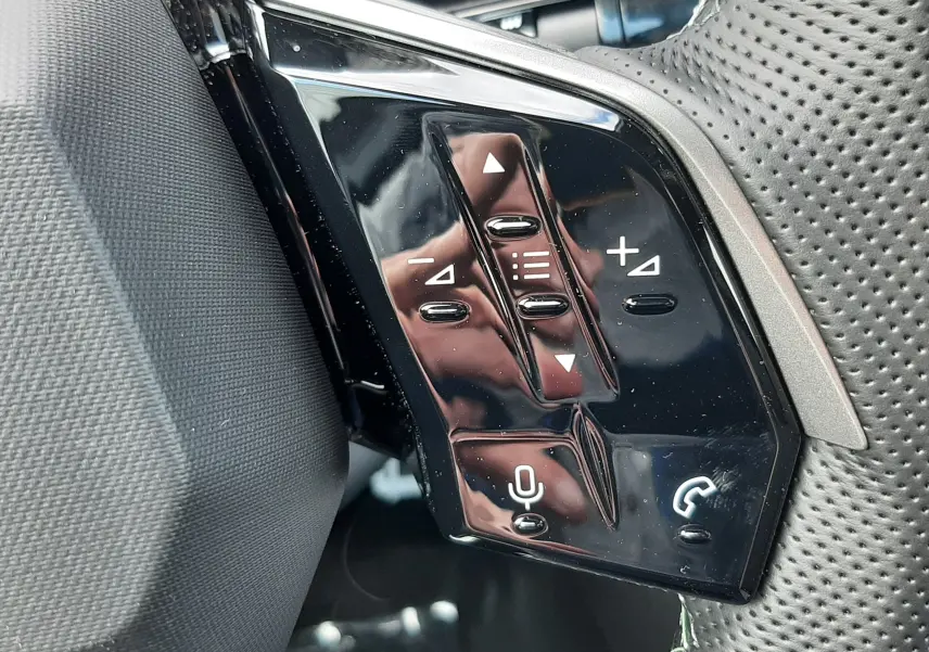 Gros plan sur les commandes multifonctions noires à droite du volant perforé du Peugeot 3008 gris titane 2026.