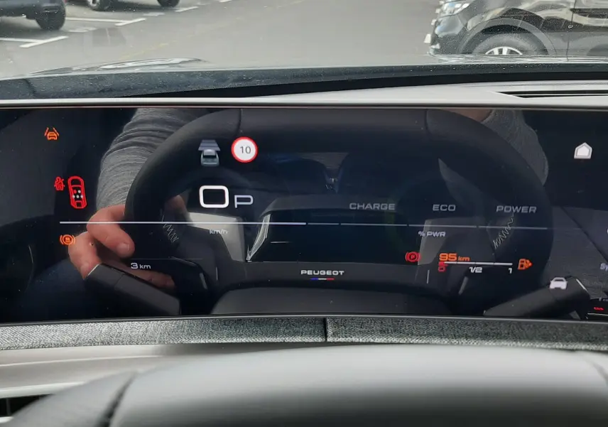 Vue intérieure du tableau de bord numérique du Peugeot 3008 hybride, affichant la vitesse et l'autonomie restante.