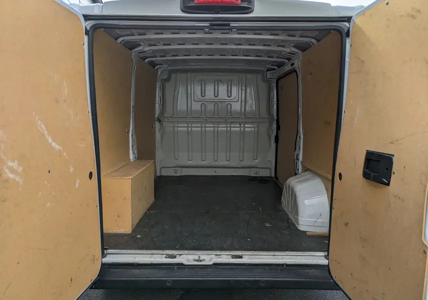 Vue arrière du fourgon blanc FIAT Ducato 2019 avec portes ouvertes montrant l'intérieur vide et ses panneaux en bois.