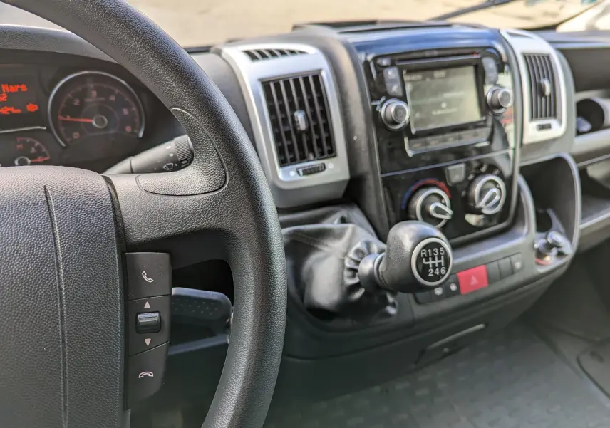 Vue intérieure du tableau de bord du Fiat Ducato Fourgon 2019, avec volant noir et levier de vitesses manuel.