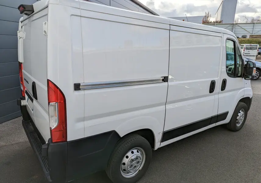 Vue 3/4 arrière droite d'un FIAT Ducato Fourgon blanc de 2019 avec porte latérale coulissante et feux arrière rouges.