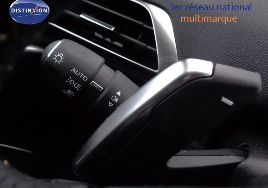 Détail du commodo d'éclairage et palette de changement de vitesse dans l'habitacle d'un Peugeot 3008 gris Artense 2023.