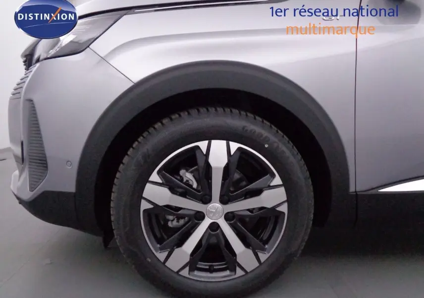 Gros plan sur la roue avant gauche d’un Peugeot 3008 gris Artense métal avec jante alliage bicolore en 2023.