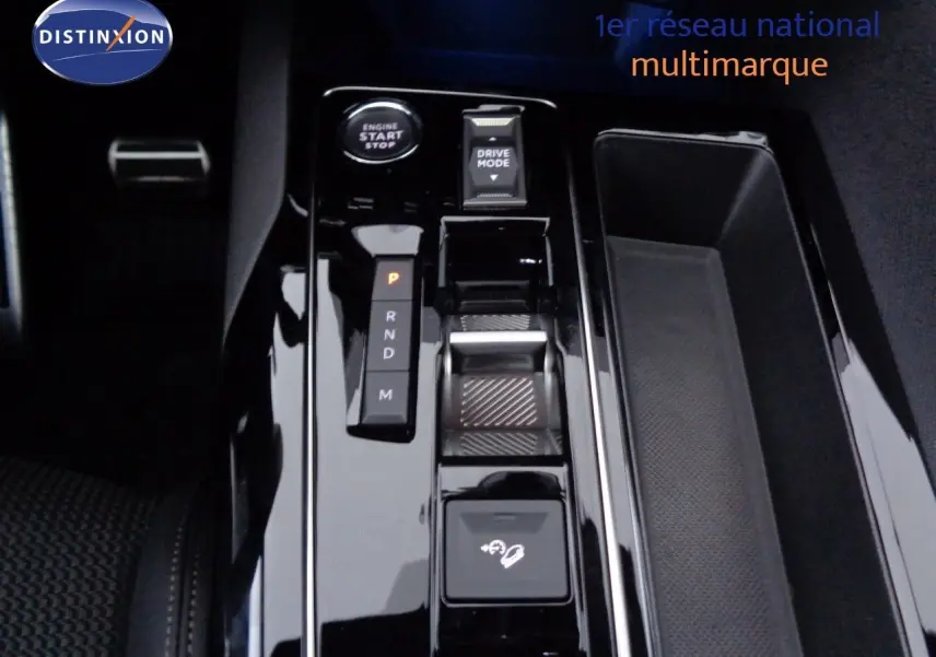Gros plan sur la console centrale noire brillante du Peugeot 3008 2023, avec levier de vitesses automatique et bouton start/stop.