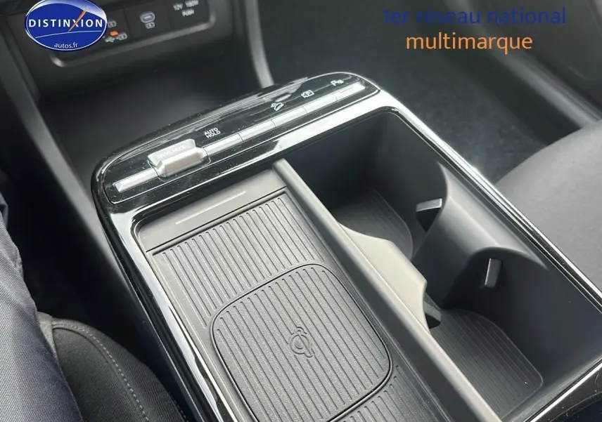 Gros plan sur la console centrale du Hyundai Tucson 2025 vert cyprès, mettant en valeur le chargeur sans fil et les porte-gobelets.