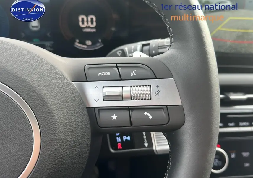 Gros plan sur le volant cuir multifonction du Hyundai Tucson 2025, avec commandes audio et affichage numérique en arrière-plan.