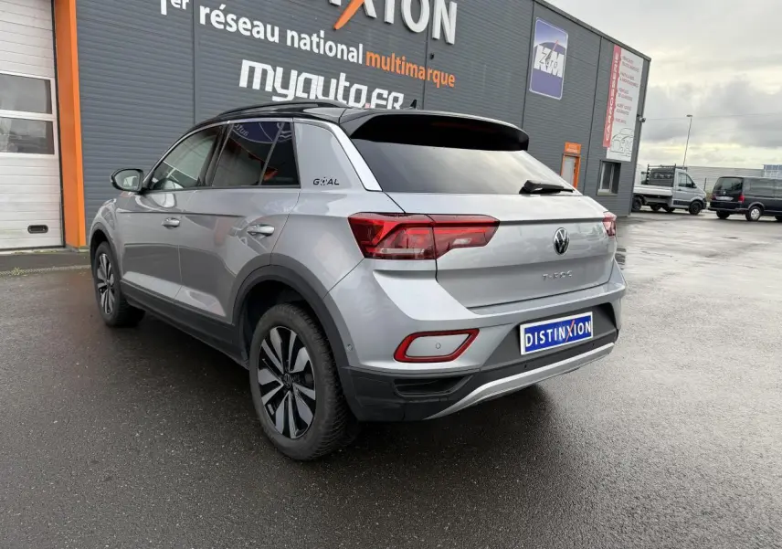 Vue 3/4 arrière droite d’un Volkswagen T-Roc argent pyrite métallisé avec jantes alliage et logo Goal sur le montant arrière.