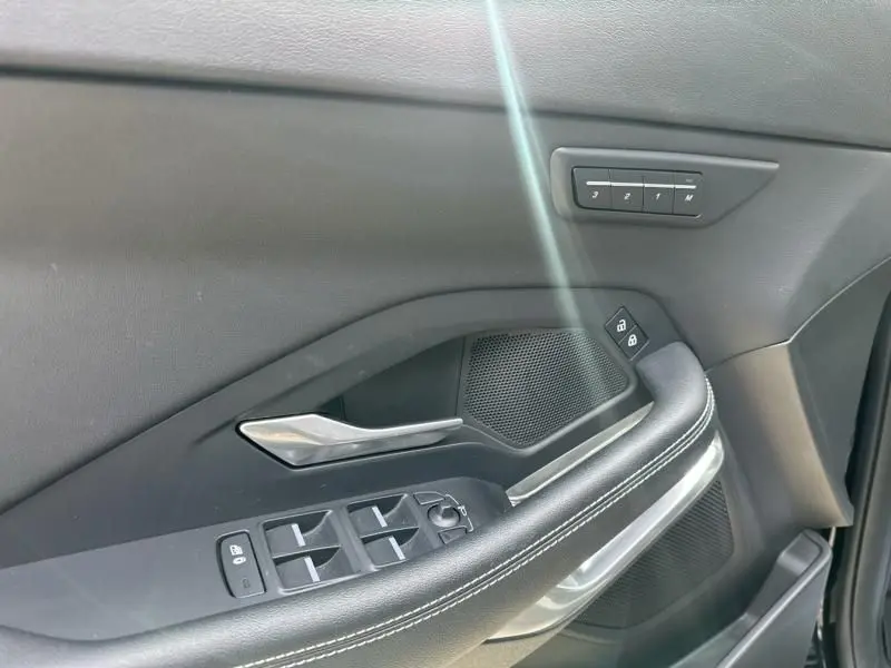 Détail de la porte avant gauche noire du Jaguar E-PACE 2021, avec commandes de vitres et bouton mémoire sièges.