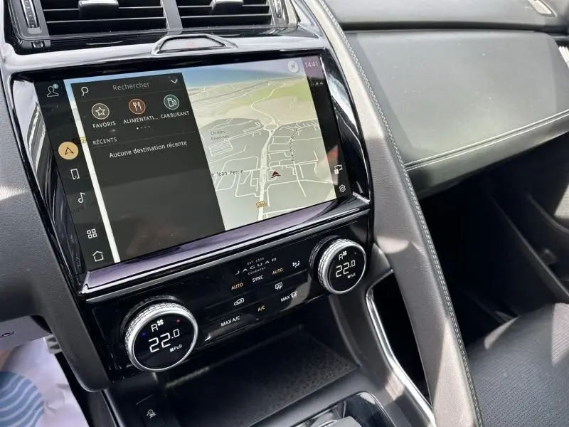 Vue rapprochée de la console centrale du Jaguar E-PACE noir 2021, avec écran tactile et commandes de climatisation digitales.
