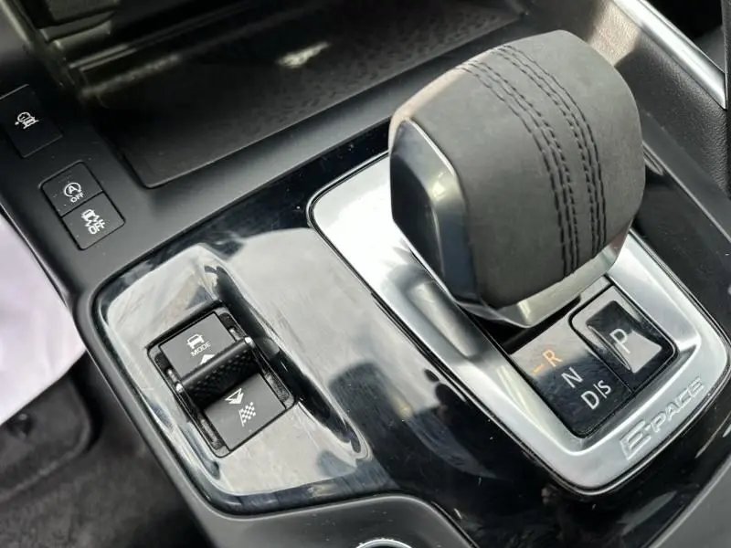 Gros plan sur le levier de vitesses en alcantara et la console centrale noire du Jaguar E-PACE D165 MHEV R-DYNAMIC S 2021.