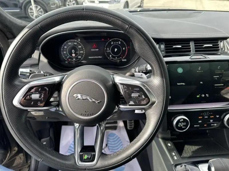 Vue intérieure centrée sur le volant noir perforé du Jaguar E-PACE 2021 avec tableau de bord numérique et écran tactile.