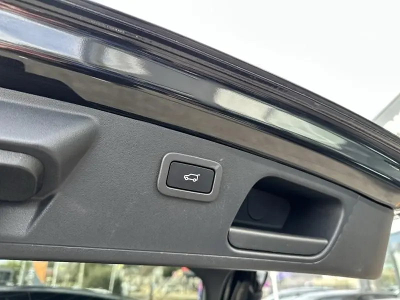 Détail du bouton d'ouverture électrique du coffre sur la partie intérieure du hayon noir du Jaguar E-PACE 2021.