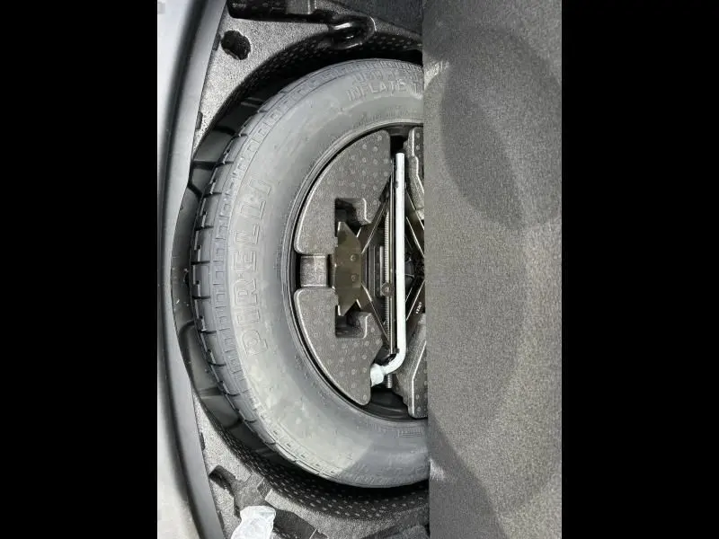 Gros plan sur la roue de secours Pirelli dans le coffre du Jaguar E-PACE noir, version D165 MHEV R-DYNAMIC S 2021.