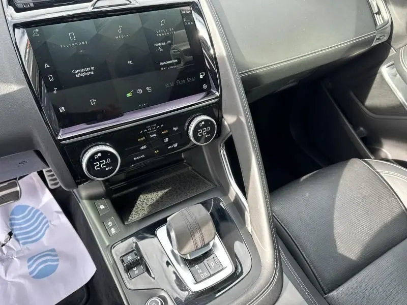Vue intérieure centrée sur la console centrale du Jaguar E-PACE 2021, avec écran tactile et levier de vitesse cuir noir.