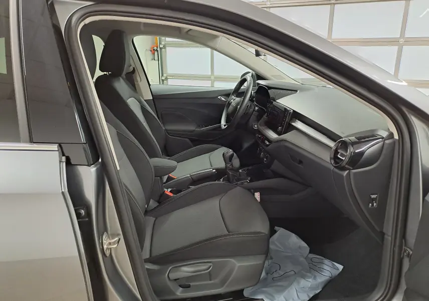 Vue intérieure côté conducteur de la Skoda Fabia 2025 gris graphite, sièges tissu noirs et tableau de bord moderne.