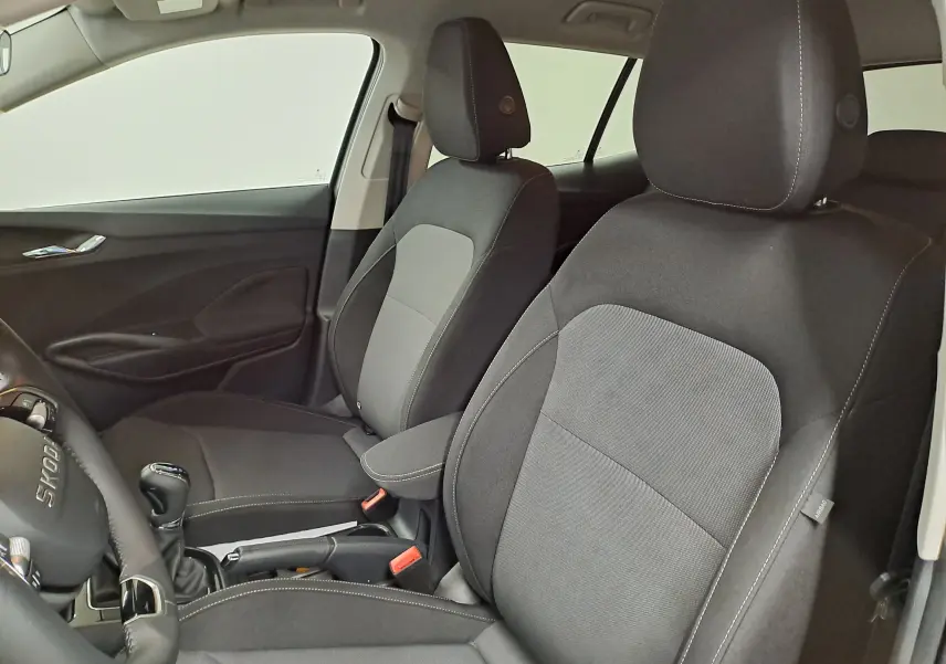 Vue intérieure côté conducteur et passager avant de la Skoda Fabia 2025 avec sièges tissu gris et volant cuir.
