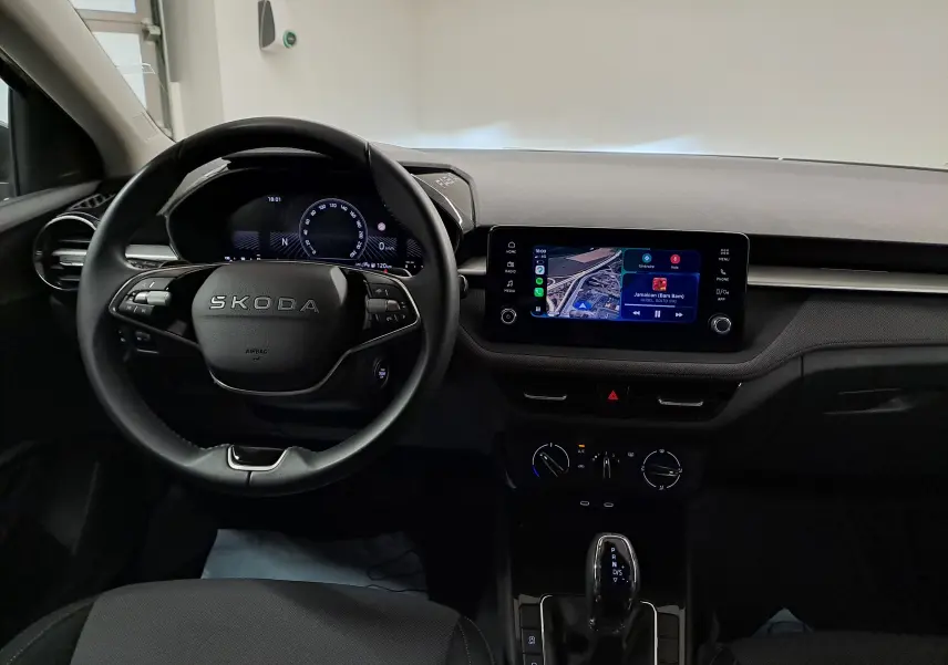 Vue intérieure du tableau de bord de la Skoda Fabia 2025, avec volant multifonction et écran tactile central allumé.