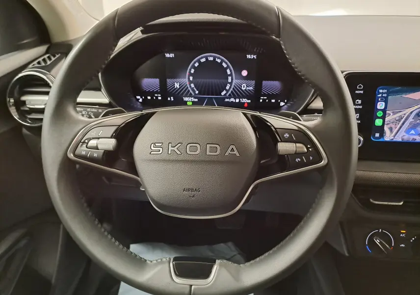 Vue rapprochée du volant noir de la Skoda Fabia 2025 avec tableau de bord numérique et écran multimédia visible.