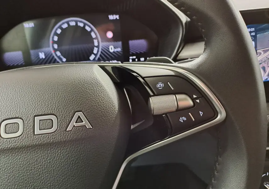 Gros plan sur le volant noir de la Skoda Fabia 2025, avec commandes intégrées et tableau de bord numérique en arrière-plan.