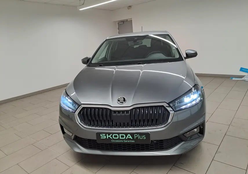 Vue avant d'une Skoda Fabia 2025 gris graphite avec calandre noire et phares LED allumés en intérieur.