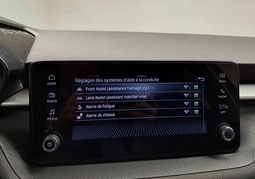 Écran tactile central de la Skoda Fabia 2025 montrant les réglages des aides à la conduite, interface noire et boutons tactiles.