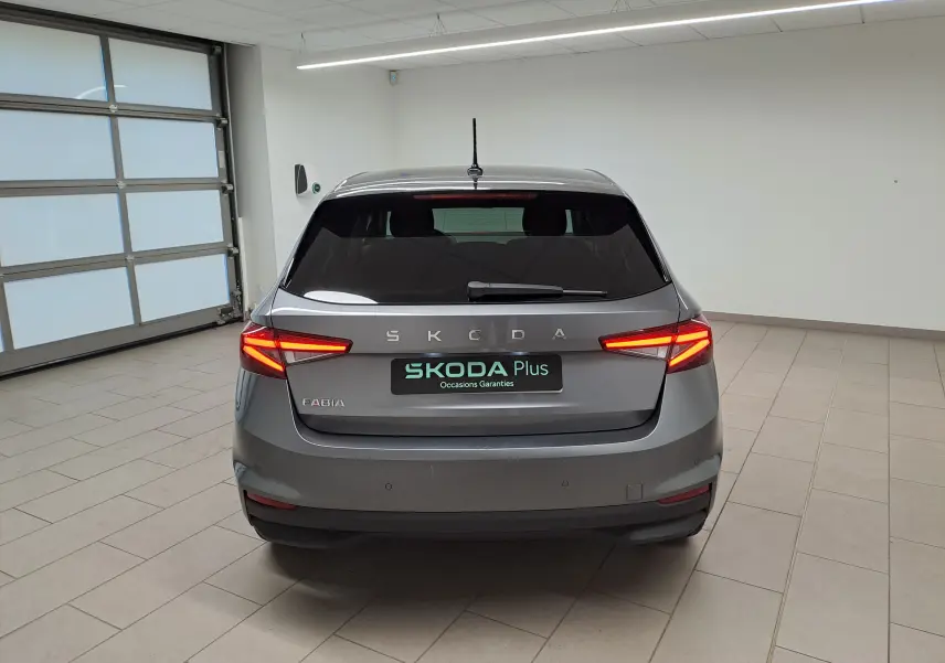 Vue arrière d'une Skoda Fabia gris graphite avec feux allumés et vitres arrière surteintées en intérieur.