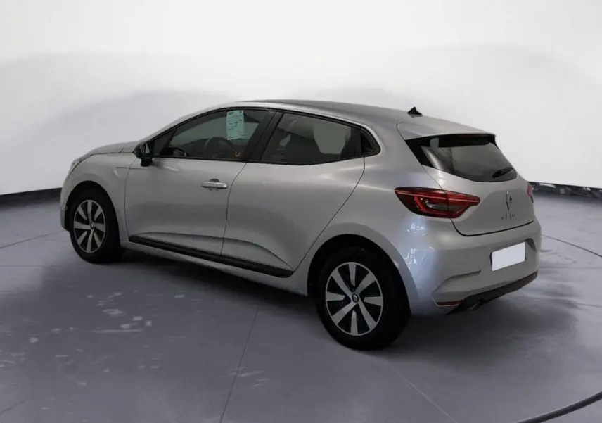 Vue 3/4 arrière côté gauche d'une Renault Clio gris clair 2022 avec jantes noires et vitres teintées.