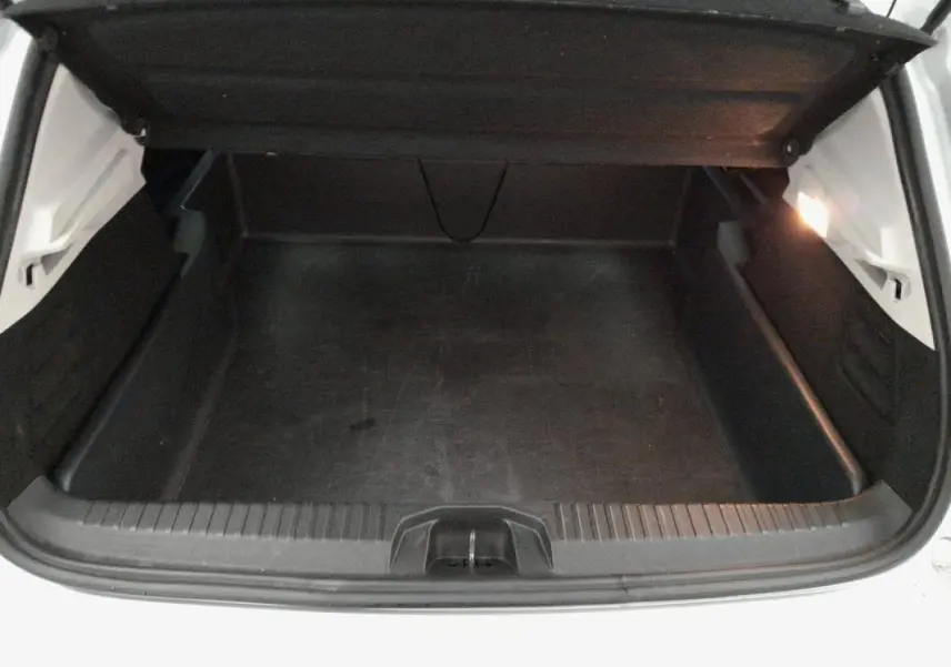 Coffre ouvert vu de face d'une Renault Clio gris clair, montrant l'espace de chargement vide et l'éclairage intérieur.