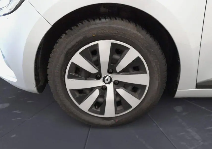 Gros plan sur la roue avant gauche d’une Renault Clio gris clair 2022 avec jante alliage au design moderne.