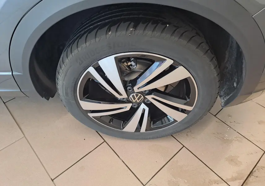 Gros plan sur la roue avant droite du Volkswagen T-Roc 2025 gris Indium avec jante alliage bicolore distinctive.