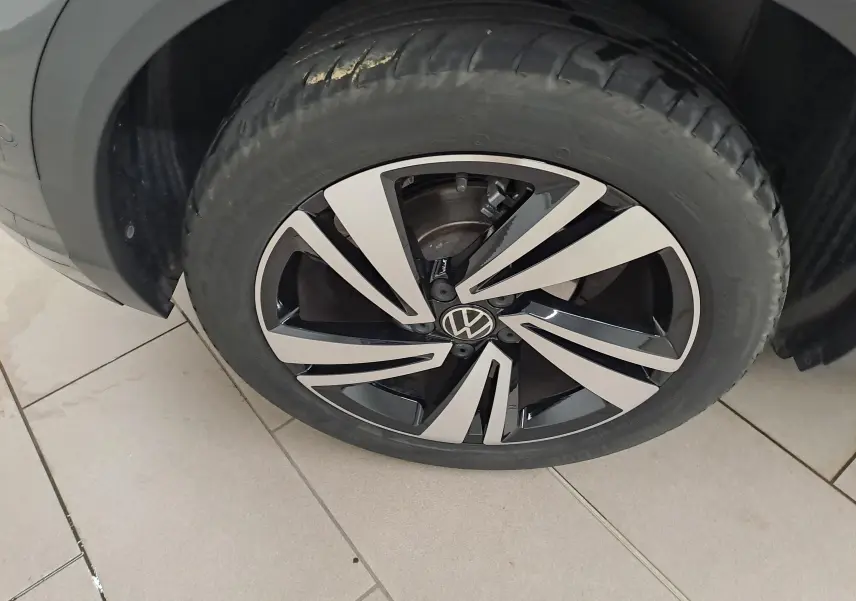 Gros plan sur la roue avant droite du Volkswagen T-Roc 2025, jante alliage bicolore noir et argent avec logo VW au centre.